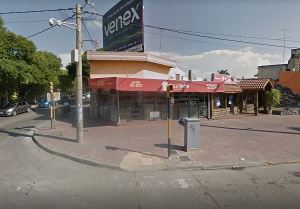 Edificio comercial con fachada beige y roja, letrero 