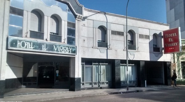 Hotel El Virrey: fachada blanca con arcos, letrero verde y rojo, entrada principal y ventanas grandes.