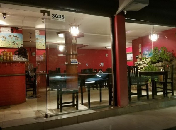 Restaurante Palito Rojo: fachada con mesas negras, paredes rojas y decoración interior iluminada. Entrada vidriada.