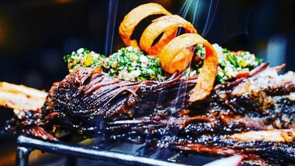 Asado Goulu: Carne jugosa, humeante, acompañada de ensalada verde y cebolla dorada, lista para disfrutar.