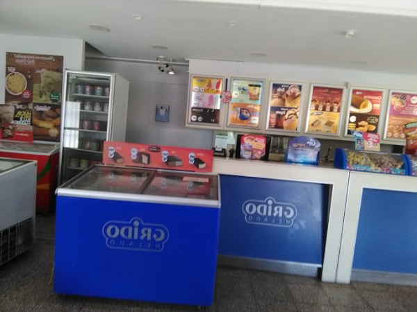 Mostrador de helados con vitrina azul y variedad de productos expuestos en estantes.