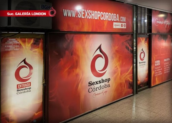 Tienda Sex Shop Córdoba con fachada roja y logo en forma de gota. Anuncios y entrada visibles. Galería pública.