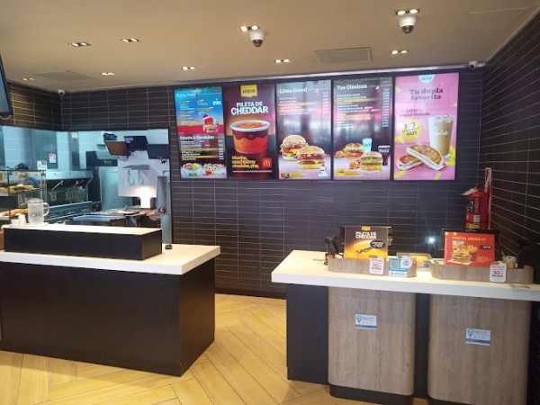 Interior de McDonald's con mostradores, menú en la pared y productos expuestos sobre el mostrador.