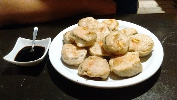 Plato con empanadas doradas y salsa oscura en Palito Rojo. Ambiente cálido y acogedor.