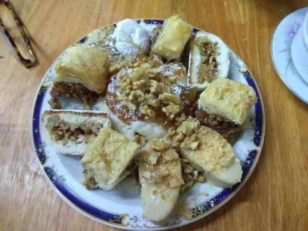 Plato de dulces tradicionales en Nur, con rellenos de nueces y miel, sobre mesa de madera.