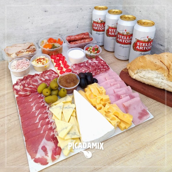 Picada Mix: tabla con embutidos, quesos, aceitunas y pan, acompañada de latas de Stella Artois.