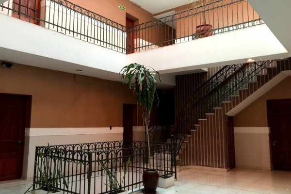 Interior del Gran Savoy: escalera elegante, barandillas negras, planta alta y puertas marrones. Ambiente acogedor y sofisticado.
