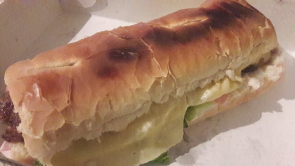 Sandwich de Pizza Piola: pan dorado con carne, queso derretido y ensalada fresca. Atractivo y apetitoso.