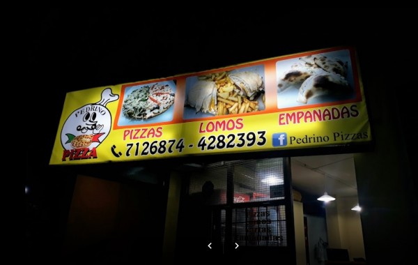 Letrero iluminado de Pedrino Pizzas ofreciendo pizzas, lomos y empanadas con imágenes de comida y contacto telefónico.