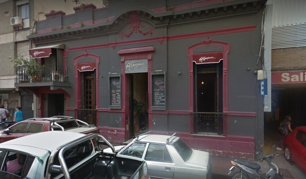 Edificio Storni con fachada gris y detalles rosados, ventanas grandes y coches estacionados frente a él.