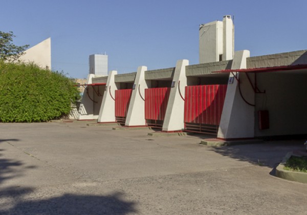 Hotel Uno Mas Uno: estructura moderna con puertas rojas, columnas blancas y cielo despejado. Diseño arquitectónico contemporáneo.