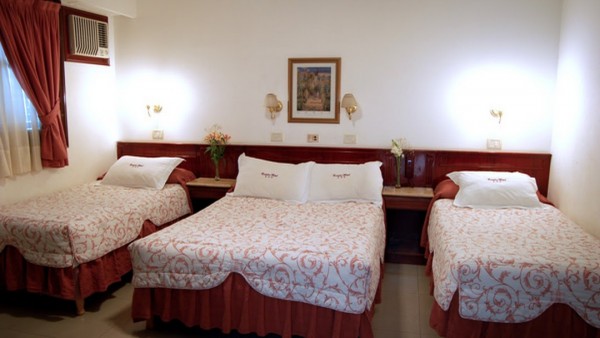 Hotel Castelar: Habitación con tres camas individuales, cortinas rojas y decoración clásica. Ambiente acogedor y elegante.