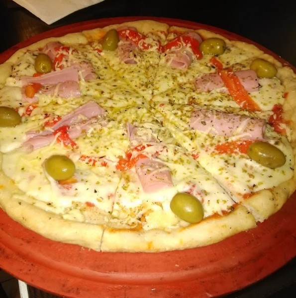 Pizza Margarita: rodajas con jamón, aceitunas verdes y queso derretido sobre masa crujiente, servida en bandeja roja.