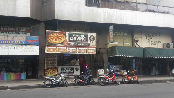 Fachada de Pizzería Da Vinci con motos estacionadas frente a ella y carteles publicitarios visibles.