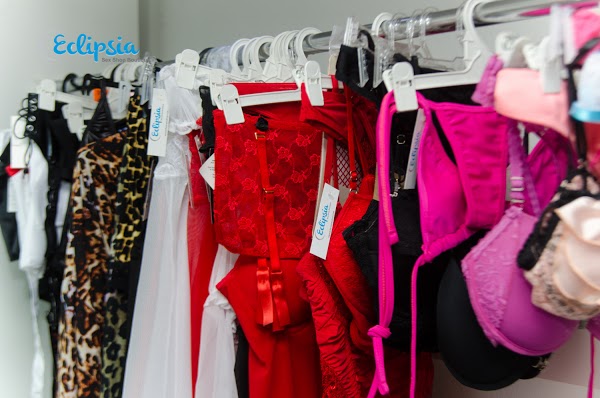 Tienda Eclipsia con variedad de lencería y disfraces colgados en perchas blancas. Ambiente iluminado y organizado.