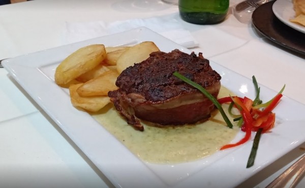 Plato de carne con patatas fritas y salsa verde en el restaurante Viejo Lobo. Presentación elegante y apetitosa.