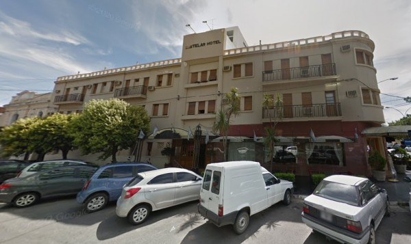 Hotel Castelar: Edificio blanco con balcones, coches estacionados frente y árboles alrededor. Día soleado.