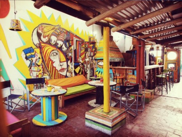Mural colorido en Morada Hostel con muebles reciclados y ambiente bohemio. Arte vibrante y decoración ecléctica.
