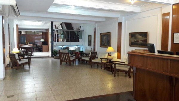 Recepción del Hotel Cristal: amplio lobby con muebles clásicos, lámparas y cuadros decorativos en tonos cálidos.