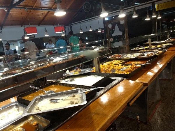 Buffet variado en Carmelo Parrilla Restaurante: platos calientes y fríos expuestos en mostrador largo bajo iluminación cálida.