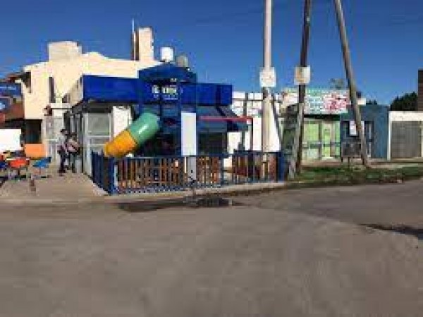 Parque infantil colorido con tobogán y estructuras azules en Grido, bajo cielo despejado.