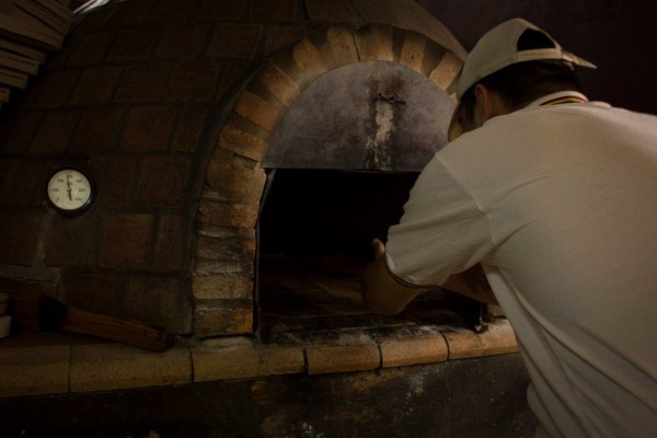 Horno de ladrillo en Macuba. Panadero con uniforme blanco trabaja cuidadosamente dentro del horno tradicional.