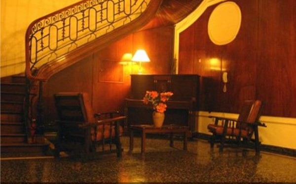 Hotel Cristal: elegante hall con escalera curva, lámparas cálidas y sillones cómodos, ambiente acogedor y sofisticado.