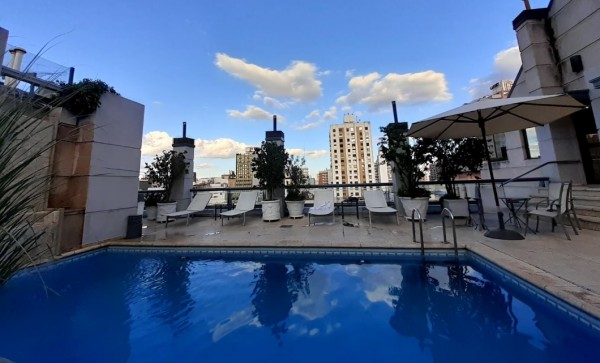 Terraza del Windsor Hotel & Tower con piscina azul, sillas blancas y vista urbana. Cielo despejado.