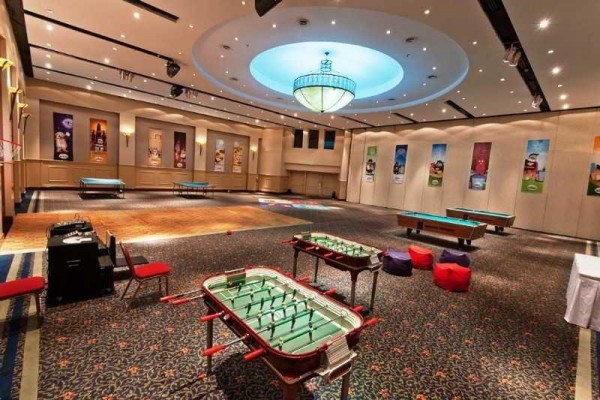 Salón amplio con mesas de futbolín y billar, iluminación cálida y decoración moderna en Holiday Inn Córdoba.
