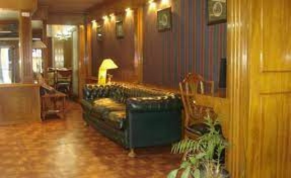 Lobby del Kent Apart Hotel con sofás negros, suelo de madera y decoración clásica.