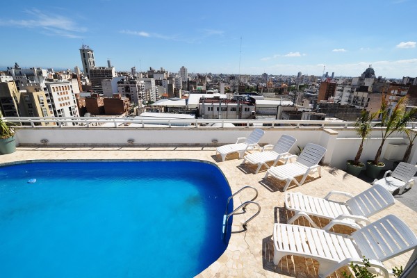 Piscina azul en terraza con tumbonas blancas y vista panorámica de la ciudad desde Amerian Córdoba Park Hotel.