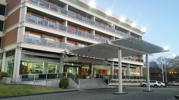 Edificio moderno con balcones y entrada techada. Letrero 