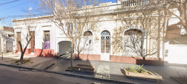 Fachada de edificio antiguo con arcos y rejas, posiblemente local comercial o taller.